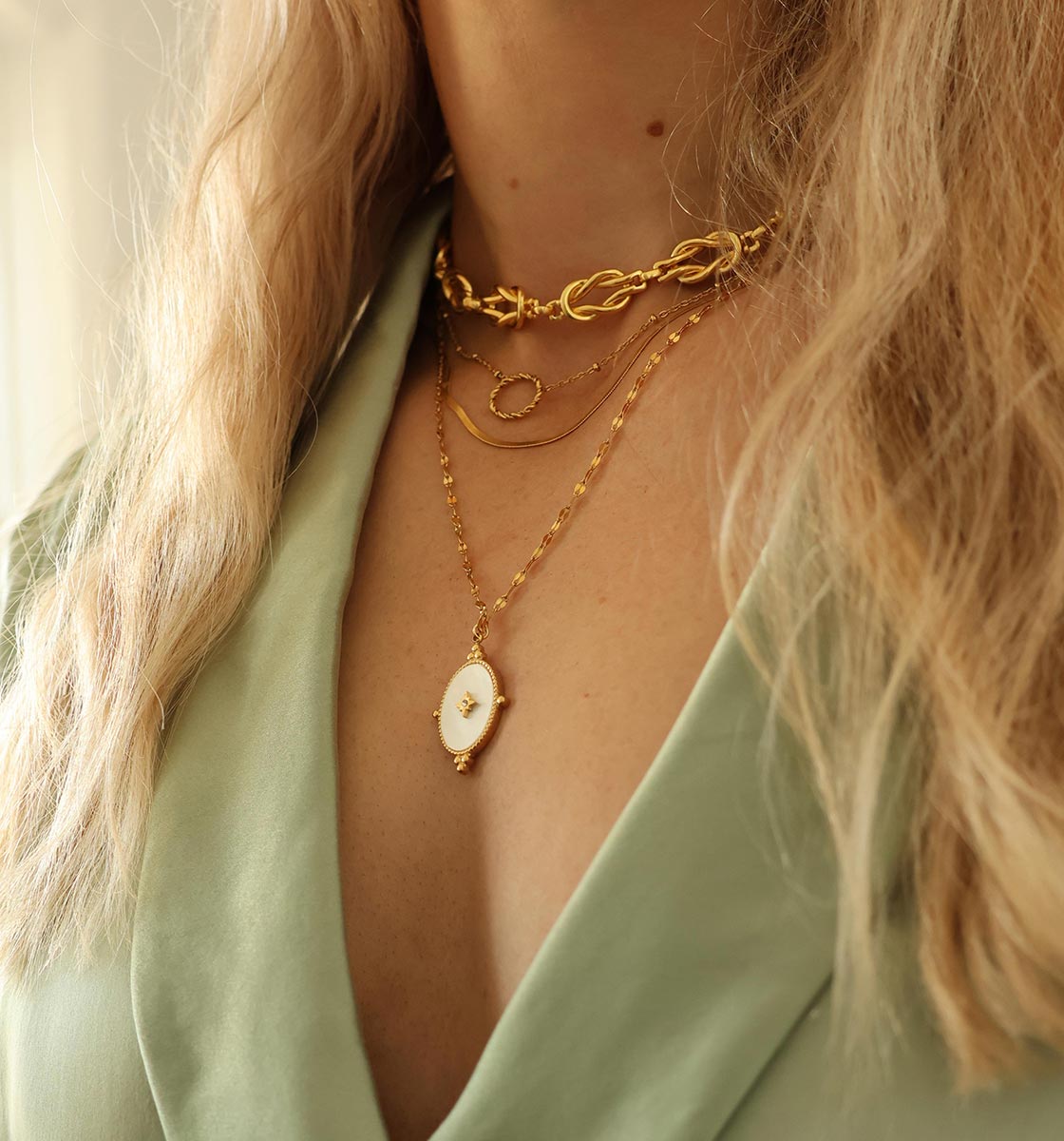 Closeup on neck wearing layered gold necklaces