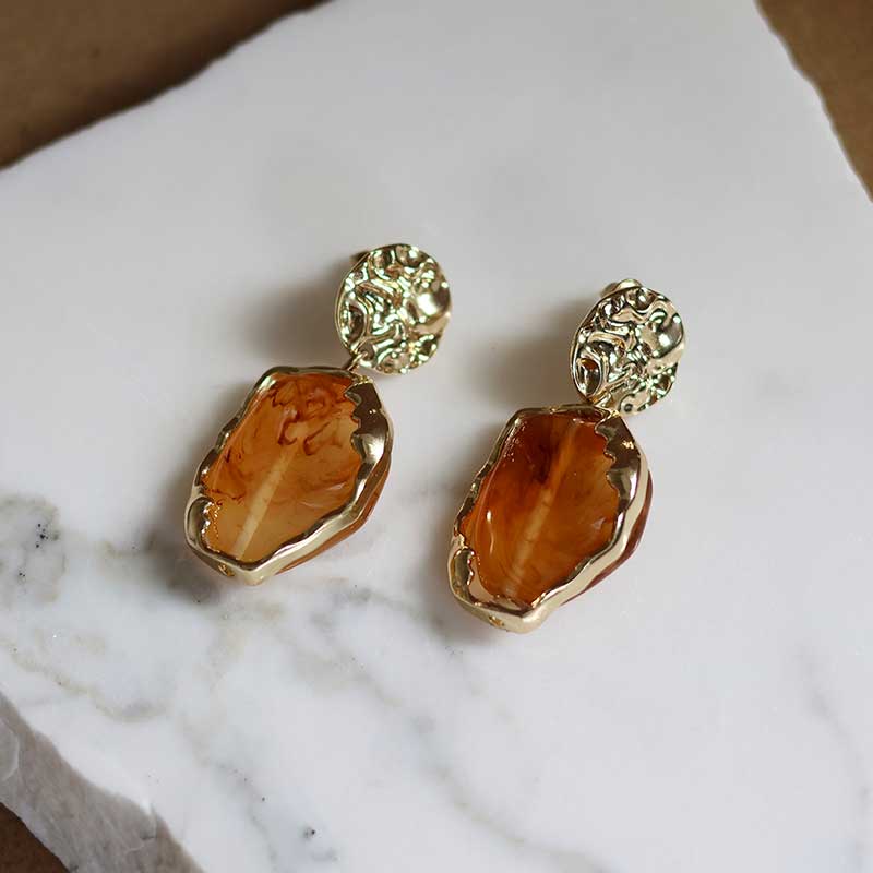 Gold drop earrings with hollow acrylic resin, called Alethea Earrings by Dear Henley on a white marble background